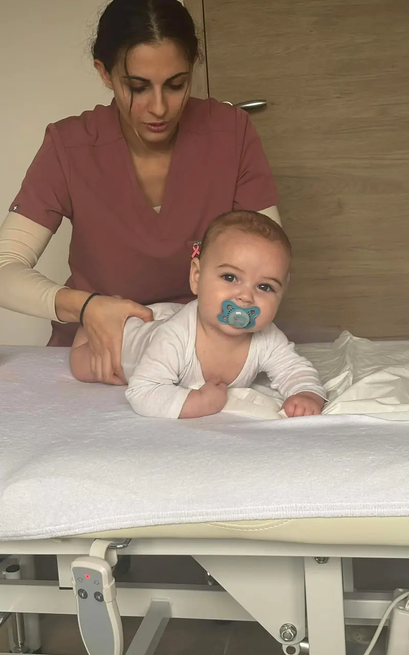Un bébé assis sur la table de soin, accompagné par Melissa